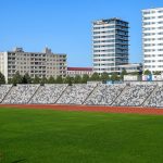 A lone runner on a green track with modern buildings in Tallinn, Estonia. Bright summer day.